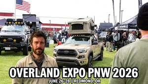Steven Marty at Overland Expo PNW 2026 in front of a black Ford truck and tan Toyota Tacoma with rooftop tent